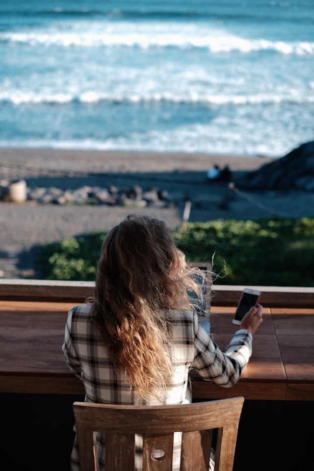 Woman using her phone with a beach view